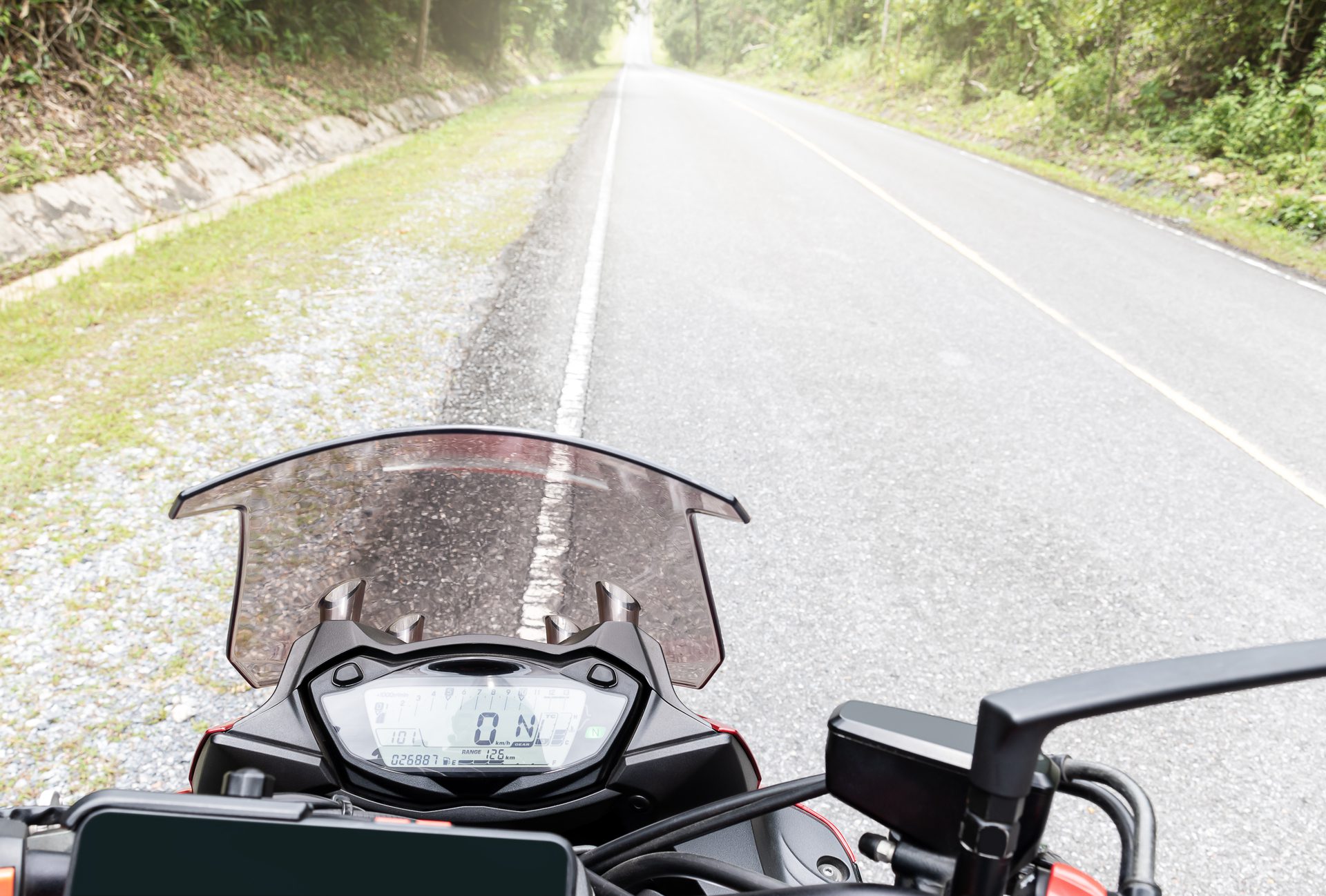 Motociklininkas vilkintis lietaus aprangą lietingame kelyje.